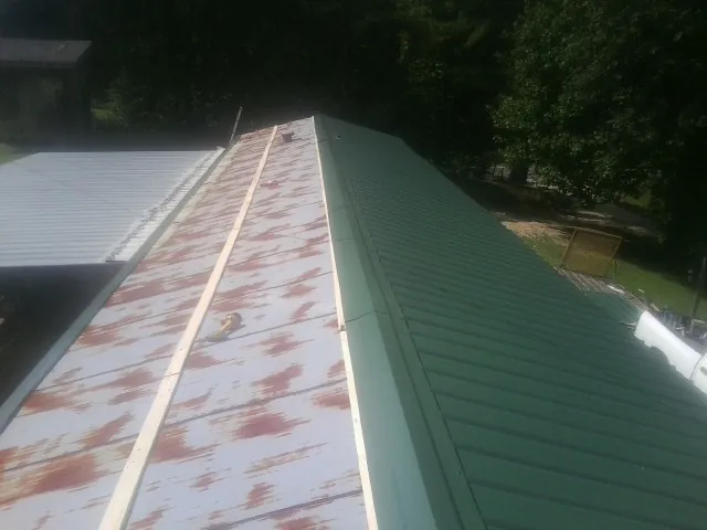 Old rusted panels beside newly installed green metal roofing — Wind Damage Roof Repair by Roofing Brothers in Robbins