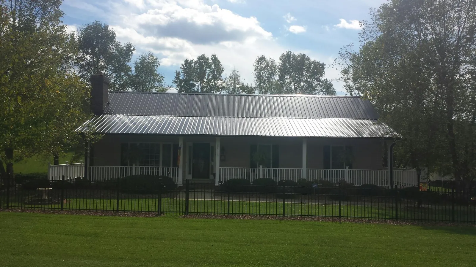 Gray metal roof on a brick ranch with a full width front porch — Gutter Guard Installation work by our crew in Robbins